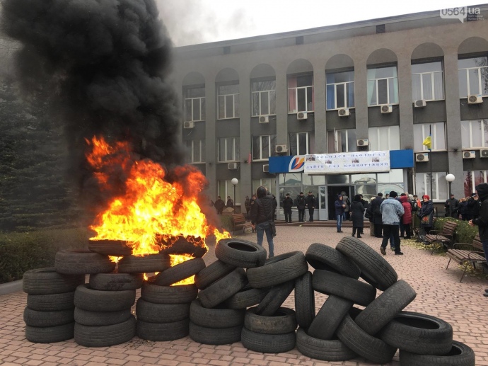 На площади перед входом в здание лежат шины, некоторые из них горят
